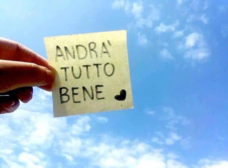 Una mano regge un biglietto su un cielo blu con nuvole. Il biglietto recita "ANDRÀ TUTTO BENE" con un cuoricino disegnato sotto, che riecheggia la speranza durante l'emergenza coronavirus e l'ascesa dello smart working.