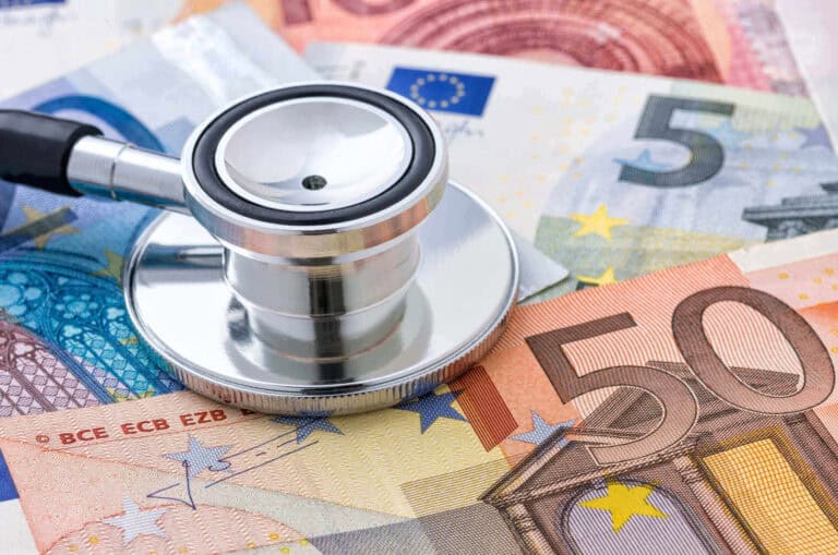 Uno stetoscopio appoggiato sopra varie banconote in euro, tra cui quelle da 5, 20 e 50 euro, a simboleggiare il rischio reddito e la salute finanziaria associati alle coperture mediche.