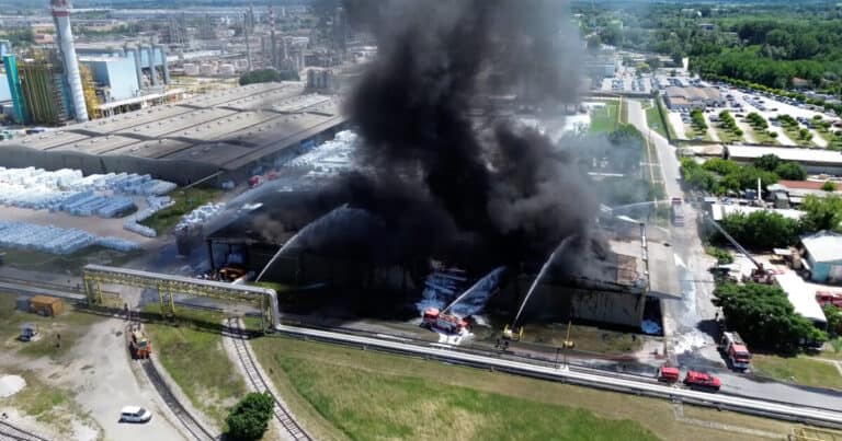 Incendio in un'azienda industriale con fumo nero e fiamme visibili, intervento dei vigili del fuoco.