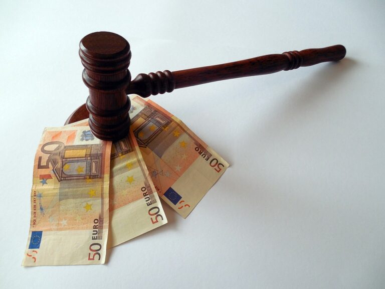 Un martelletto da giudice in legno poggia su tre banconote da cinquanta euro, a simboleggiare il legame tra legge, giustizia e denaro su uno sfondo bianco.
